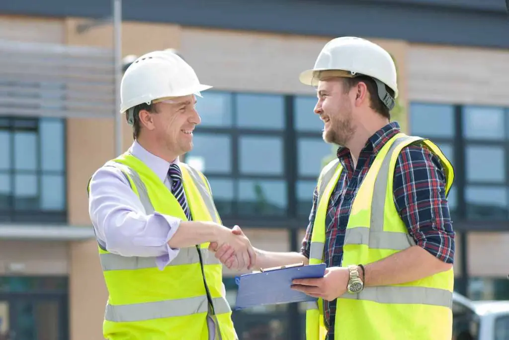 builder and architect shake hand in front of building